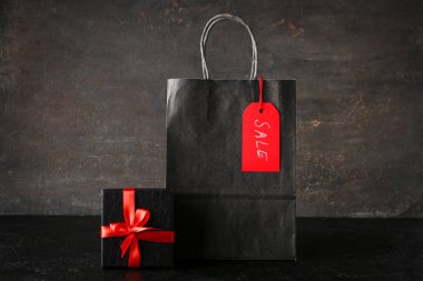 Koyu renk grunge masasında alışveriş çantası ve hediye kutusu. Kara Cuma indirimi