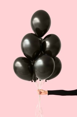Pembe arka planda güzel hava balonları tutan bir kadın. Kara Cuma konsepti