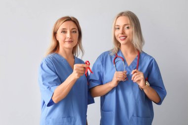 Gri arka planda kırmızı kurdeleli kadın doktorlar. Dünya AIDS Günü konsepti