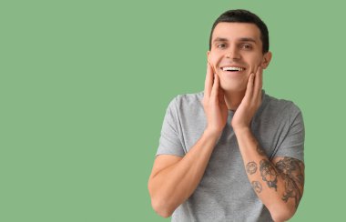 Yeşil arka planda traş olduktan sonra yakışıklı bir genç.