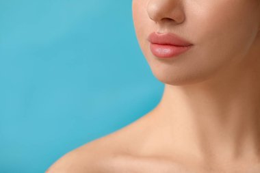 Mavi arka planda güzel dudakları olan genç bir kadın, yakın plan.