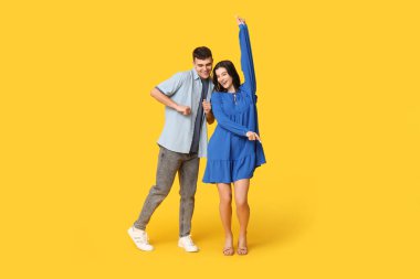 Sarı arka planda dans eden mutlu genç çift