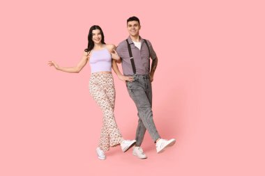 Mutlu genç çift pembe arka planda dans ediyor