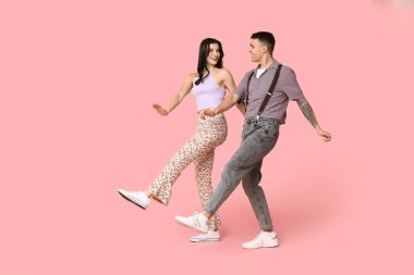 Mutlu genç çift pembe arka planda dans ediyor