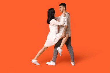 Turuncu arka planda dans eden güzel bir çift.