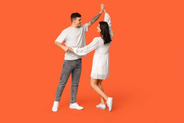 Turuncu arka planda dans eden güzel bir çift.