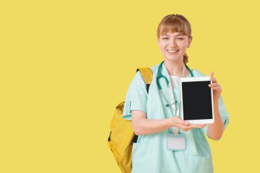 Sarı arka planda tablet bilgisayarı olan kadın stajyer.