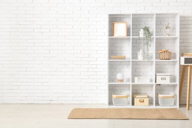 Beyaz tuğla duvarın yanındaki modern raf ünitesi