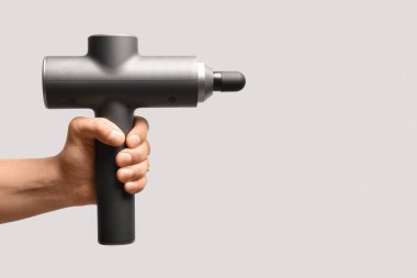 Beyaz arka planda vurmalı masaj aleti olan bir erkek el.