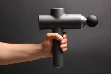 Siyah arka planda vurmalı masaj aleti olan erkek el, yakın plan.