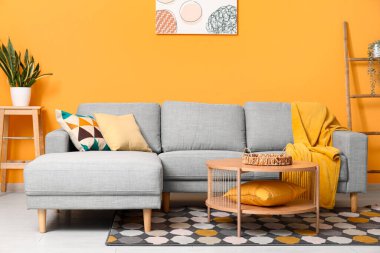 Güzel oturma odasının içinde rahat bir kanepe, çiçekler, yastıklar ve kahve masası.