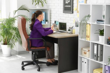 Ofisteki iş yerinde dizüstü bilgisayar kullanan kadın ofis çalışanı.