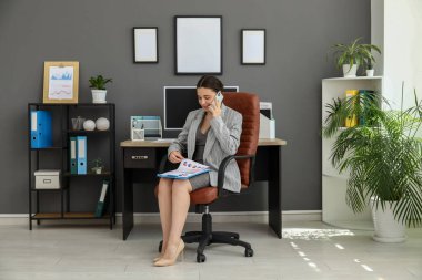 Şık bir ofiste çalışan, cep telefonuyla konuşan bir ofis çalışanı.