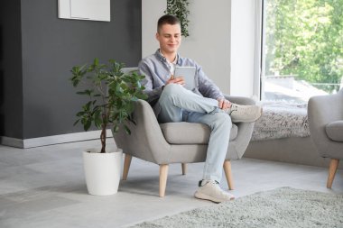 Modern ofis koltuğunda oturan tablet bilgisayarlı genç bir erkek serbest yazar.