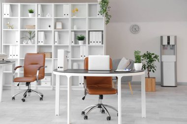 Çalışma alanları, raf ünitesi ve koltukları olan açık uzay ofisinin içi