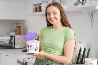 Mutfakta dondurma kovası olan genç bir kadın.