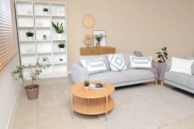 Rahat kanepesi, sehpası, raf ünitesi ve saksısı olan şık bir oturma odası.