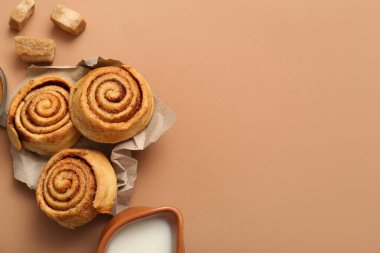 Nefis tarçınlı rulo ve kahverengi arka planda bir sürahi süt.