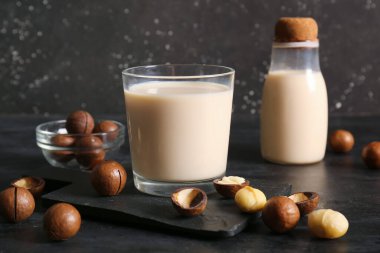 Siyah arka planda bir şişe taze Macadamia sütü.