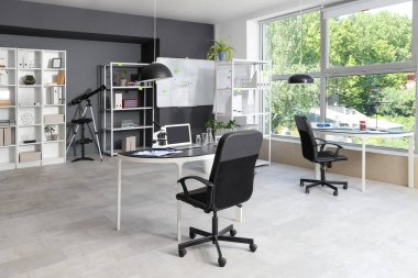 Masaları, raf üniteleri ve beyaz tahtası olan laboratuvarın içi