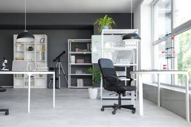 Masaları ve raf üniteleri olan laboratuvarın içi