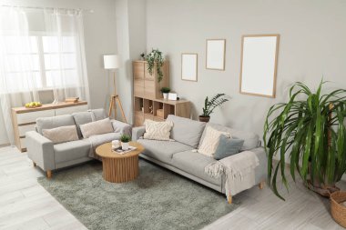 Gri kanepeleri, ahşap sehpası ve çiçekleri olan şık bir oturma odası.