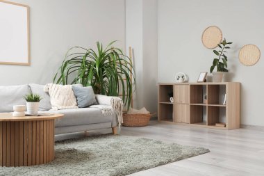 Gri kanepesi, ahşap sehpası ve çiçekleri olan şık bir oturma odası.