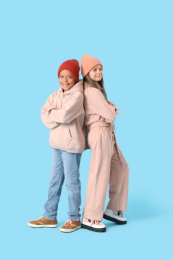 Mavi arka planda kışlık giysiler içinde şirin, mutlu çocuklar.