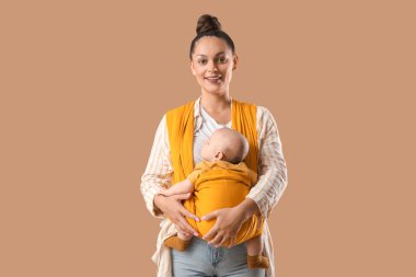 Güzel, genç, mutlu bir anne. Bej arka planda küçük şirin bir bebeği var.