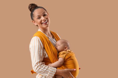 Güzel, genç, mutlu bir anne. Bej arka planda küçük şirin bir bebeği var.