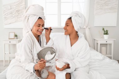 Mutlu, genç, Afro-Amerikan anne ve aynalı kızı evde maske takıyor.