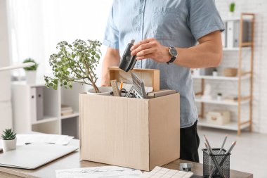 Kovulan genç adam kişisel eşyalarını ofiste kutuya koydu.