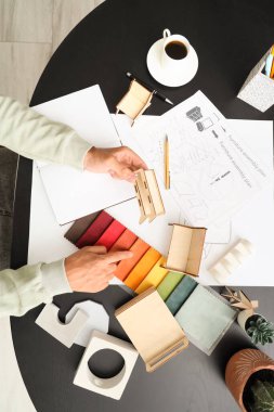Siyah masa üzerinde minyatür model ve kumaş örnekleri olan erkek mobilya tasarımcısı.