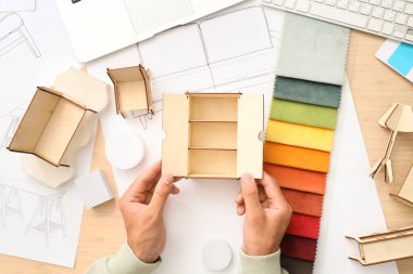 Masada çalışan minyatür modelli erkek mobilya tasarımcısı.