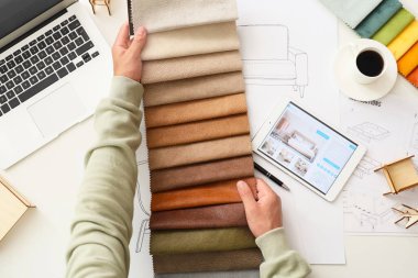 Beyaz masa üzerinde kumaş örnekleri olan erkek mobilya tasarımcısı.