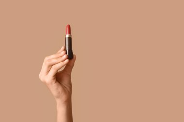 Kahverengi arka planda ruj izi olan bir kadın el.