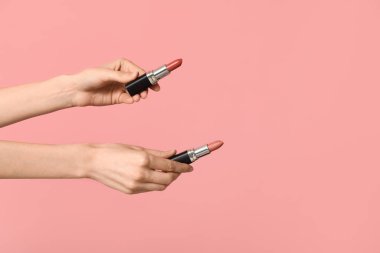 Pembe arka planda farklı ruj izleri olan kadın elleri.