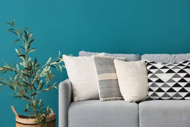 Yastıklı ve mavi duvarlı şık gri kanepe.