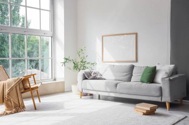 Gri kanepesi, koltuğu ve pencerenin yanında kitapları olan şık bir oda.