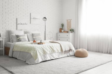 Yatak odasının içinde lamba, kahvaltı ve yatağın üstünde kitaplar var.