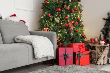 Işıl ışıl Noel ağacı, hediyeler ve kanepesi olan oturma odasının içinde.