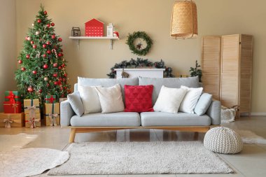Oturma odasının içinde Noel ağacı, hediyeler ve kanepe var.