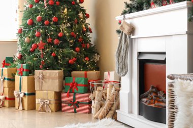 Oturma odasının içinde Noel ağacı, hediyeler ve şömine var.
