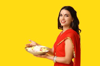 Sarı arka planda mumları ve çiçekleri olan sarili mutlu Hintli kadın. Divaly kutlaması