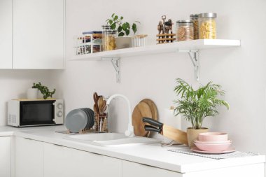 Lavabosu, rafı ve çatalı olan hafif mutfağın içi.