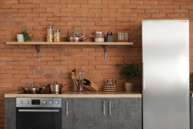 Gümüş buzdolabı, tezgah ve raflı modern mutfak.