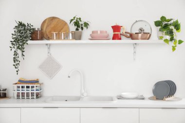 Mutfağın içinde tezgah, raf ve mutfak gereçleri var.