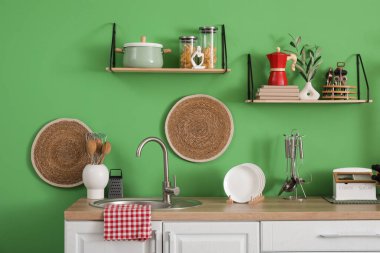 Mutfağın içinde lavabo, raf ve çatal bıçak var.