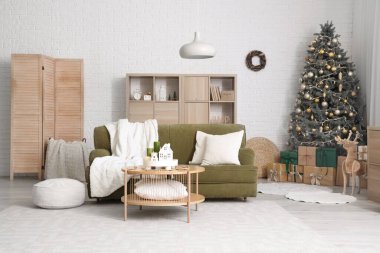 Oturma odasının içinde kanepe, Noel ağacı ve yanan mumlar var.