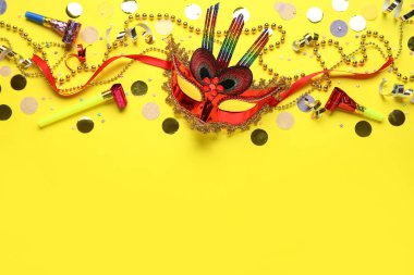 Sarı arka planda parti boynuzları ve dekoru olan karnaval maskesi.